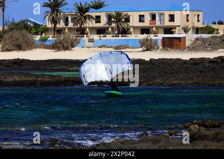 Homme plus âgé avec planche de feuille et voile à une plage rocheuse, El Cotillo, Fuerteventura, Îles Canaries, Espagne, Europe. Prise en février 2024 Banque D'Images