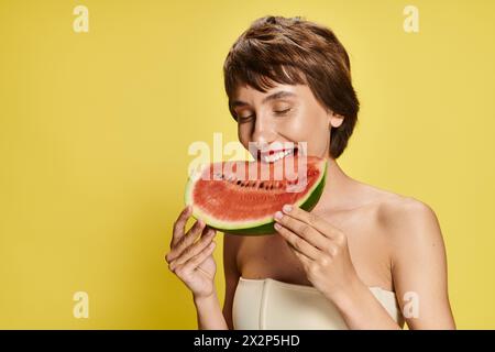 La jeune femme tient joyeusement la tranche de pastèque sur son visage. Banque D'Images