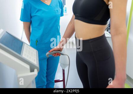 Un praticien de la santé assiste une femme avec un test de composition corporelle à l'aide d'un équipement de pointe. Banque D'Images