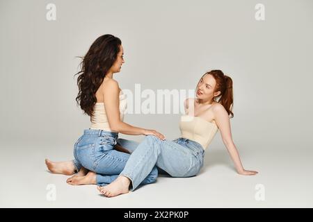 Deux femmes élégamment habillées sont assises sur le sol, plongées dans une conversation profonde. Banque D'Images