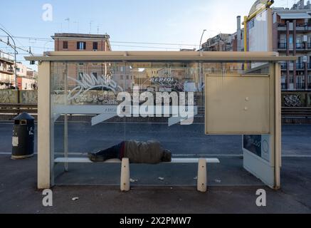 Italie, Rome : un sans-abri dort allongé sur le banc de l'arrêt de bus sur la route de Casilina Banque D'Images