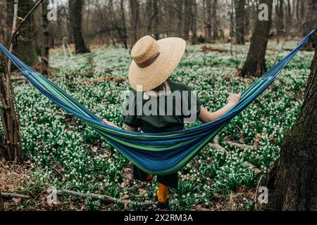 Femme portant un chapeau en osier et assis dans un hamac à la forêt Banque D'Images