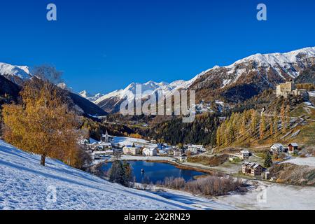 Château de Tarasp et lac près des maisons et des sommets enneigés des Alpes de Silvretta le jour ensoleillé, Tarasp, basse Engadine, Engadine, Grisons, Suisse Banque D'Images