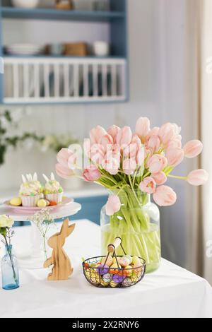Décorations de Pâques et tulipes couleur pêche sur table à la maison Banque D'Images