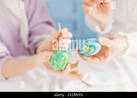 Mère et fille tenant des œufs de Pâques colorés à la maison Banque D'Images