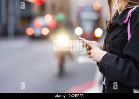 Femme tenant le téléphone portable dans la rue Banque D'Images
