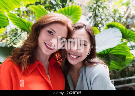 Heureux amis multiraciaux dans les occasionnels près des plantes Banque D'Images