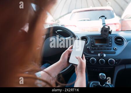 Jeune femme utilisant un smartphone en voiture Banque D'Images