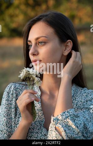 Belle jeune femme tenant des fleurs sauvages près du visage Banque D'Images