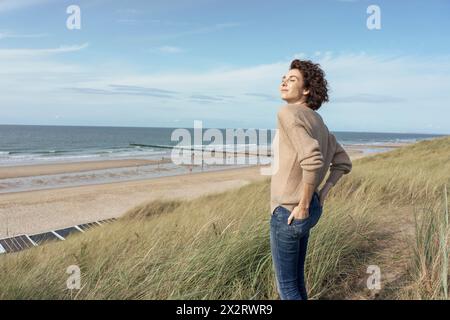 Belle femme avec les yeux fermés debout à la plage Banque D'Images