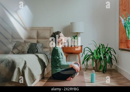 Femme méditant près du lit à la maison Banque D'Images