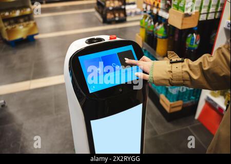 Femme interagissant avec l'assistant robotique au supermarché Banque D'Images