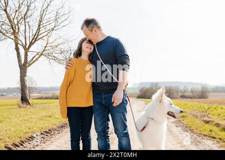 Père et fille debout avec berger suisse blanc sur le sentier Banque D'Images