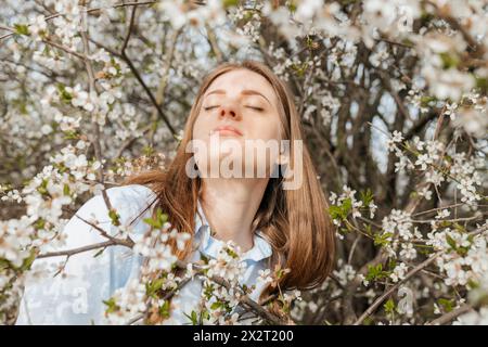 Belle femme au milieu des fleurs de cerisier sur l'arbre Banque D'Images