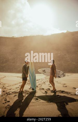 Couple avec des planches de surf parlant à la plage le jour ensoleillé Banque D'Images