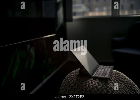 Tablet PC avec clavier maintenu sur hassock dans le bureau sombre Banque D'Images