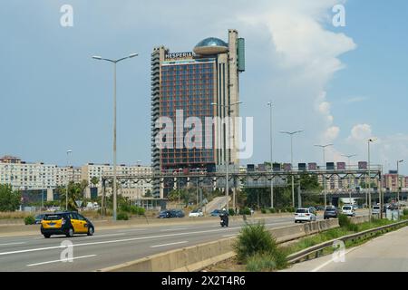 Barcelone, Espagne - 24 mai 2023 : voitures et taxi voyagent sur une route à plusieurs voies sous un ciel dégagé, avec la Tour Hesperia visible en arrière-plan. Banque D'Images
