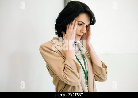 Femme d'affaires mature touchant des temples souffrant de maux de tête au bureau Banque D'Images