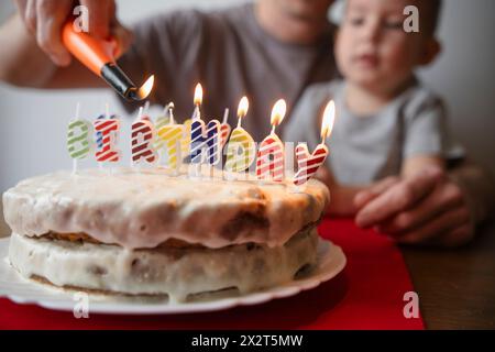 Père allumant gâteau d'anniversaire de fils à la maison Banque D'Images