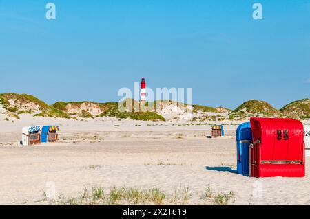 Allemagne, Schleswig-Holstein, Amrum, chaises de plage à capuche sur plage de sable avec phare en arrière-plan Banque D'Images