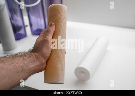 Homme remplaçant le filtre sale pour l'osmose inverse dans la cuisine. Concept d'eau de purification. Banque D'Images