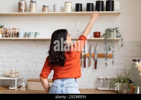 Femme atteignant l'étagère dans une cuisine moderne Banque D'Images