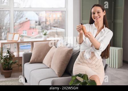 Jeune femme avec bouteille d'huile de CBD à la maison Banque D'Images