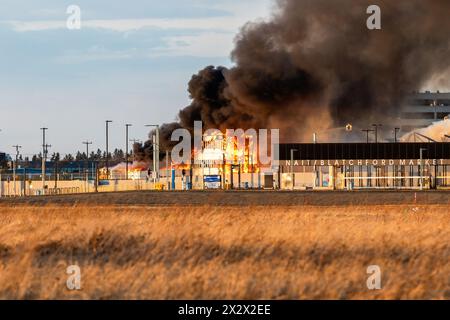 Edmonton, Canada. 22 avril 2024. Un incendie de 5 alarmes détruit un hangar aérien historique de la seconde Guerre mondiale alors que le service d'incendie d'Edmonton protège le site de la propagation à d'autres bâtiments. Le hangar qui a été construit en 1942 a été déclaré un bâtiment historique d'importance pour sa part dans l'expédition d'équipements, de troupes et d'avions pour les forces américaines en route vers la Russie. La cause de l'incendie fait actuellement l'objet d'une enquête et aucun mot n'est encore dit concernant les dommages estimés. Crédit : SOPA images Limited/Alamy Live News Banque D'Images