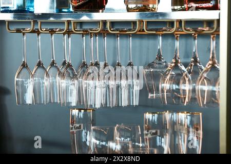 23.02.2024, Berlin, Berlin, Allemagne - des verres à champagne et à vin propres sont suspendus dans un rack dans un bar. En dessous d'eux sont utilisés des verres à bière et des verres à jus. 00 Banque D'Images