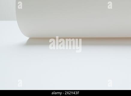 Rouler du papier blanc sur une feuille de papier vierge sur une table. Abstraction Banque D'Images