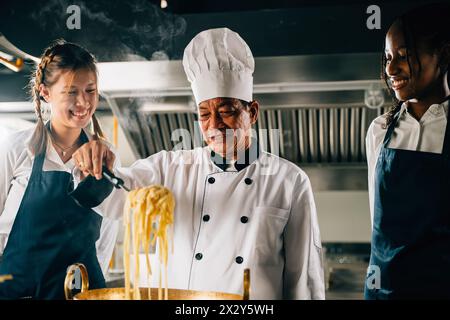 Chef éduque en cuisine. Des écolières en uniforme font de la soupe de nouilles japonaises. Enfants au poêle avec Banque D'Images