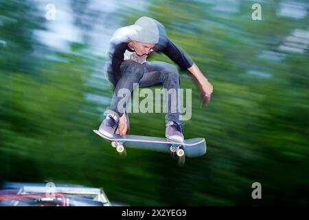 Garçon saute sur skateboard dans skatepark dans culture and Recreation Park Banque D'Images