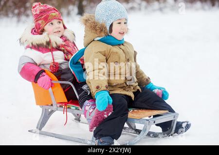 Deux petits enfants assis dans le traîneau dans le parc d'hiver Banque D'Images