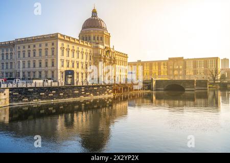 La lumière dorée du matin baigne le Palais de Berlin et le Forum Humboldt, reflétant les eaux calmes. Berlin, Allemagne Banque D'Images