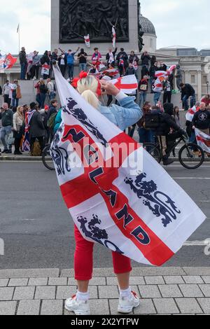 Londres, Royaume-Uni, 23 avril 2024. Les fêtards se tiennent au sommet de la colonne Nelson en chantant et en chantant des chansons de football. Un rassemblement de la Saint-Georges, en partie une célébration - et en partie une protestation, a eu lieu à Whitehall, en présence d'une grande foule de patriotes, de supporters de football et d'autres, portant des drapeaux rouges et blancs et certains en costume. Crédit : onzième heure photographie/Alamy Live News Banque D'Images