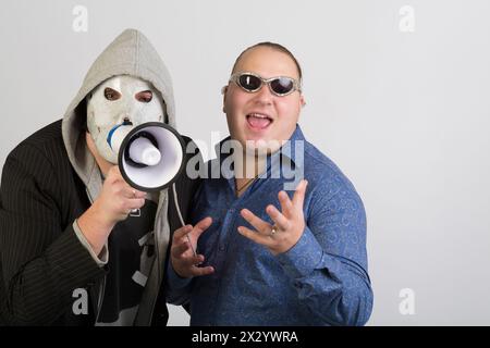Deux hommes, l'un portant un masque avec mégaphone, l'autre portant des lunettes de soleil Banque D'Images