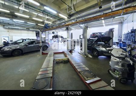 Beaucoup de voitures se tiennent dans le garage avec un équipement spécial pour la réparation. Banque D'Images