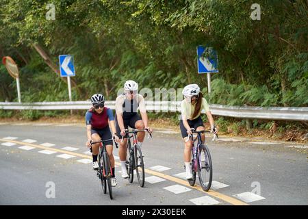 trois jeunes cyclistes asiatiques faisant du vélo à l'extérieur sur la route rurale Banque D'Images