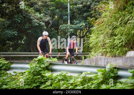 jeunes cyclistes de couple asiatique faisant du vélo sur la route rurale Banque D'Images