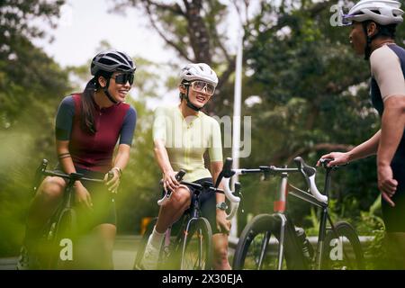 groupe de trois jeunes cyclistes asiatiques heureux discutant tout en faisant du vélo à l'extérieur Banque D'Images