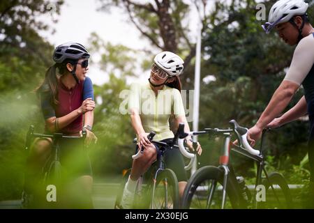 groupe de trois jeunes cyclistes asiatiques heureux discutant tout en faisant du vélo à l'extérieur Banque D'Images