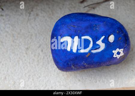 Une petite pierre commémorative bleue peinte avec le mot hébreu 'Remember' placée sur la tombe d'un soldat israélien tombé dans le cème militaire du mont Herzl Banque D'Images