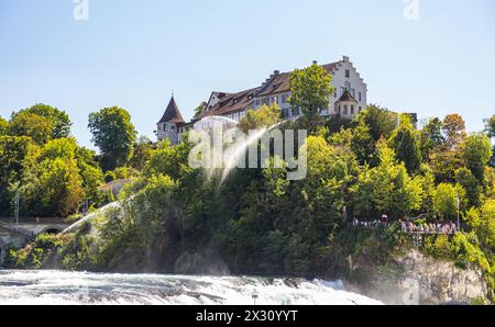 während die Feuerwehr einen Flächenbrand unterhalb des Schloss Laufen bekämpft, bestaunen auf der anderen Seiter Touristen den Rheinfall. (Neuhausen a Banque D'Images