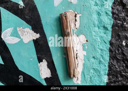Une mezouzah en bois fissurée attachée à une porte sur un vieux bâtiment coloré peint à Jérusalem. Banque D'Images