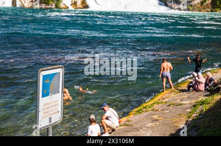 DAS Baden im Rheinfallbecken ist verboten, da wegen der Strömung Lebensgefahr besteht. Einige Touristen wagen sich trotzdem ins Wasser. (Neuhausen am Banque D'Images