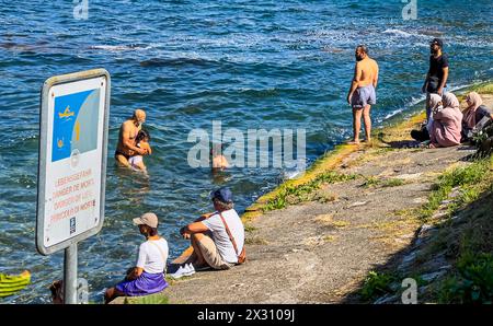 DAS Baden im Rheinfallbecken ist verboten, da wegen der Strömung Lebensgefahr besteht. Einige Touristen wagen sich trotzdem ins Wasser. (Neuhausen am Banque D'Images