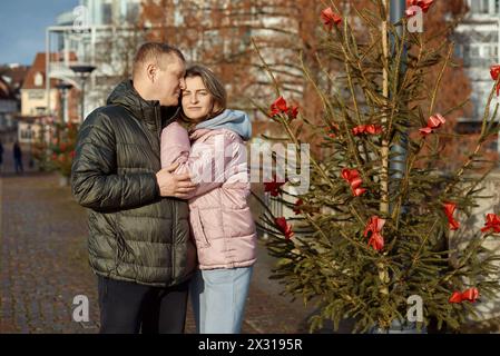 Portrait de jeunes gens attrayants, couple charmant bénéficiant de l'atmosphère chaleureuse sur la foire dans la veille de Noël. Passer du temps ensemble. Concept de national Banque D'Images