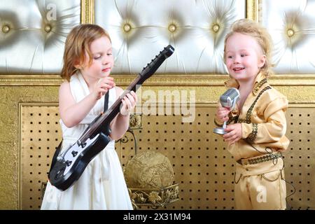 Une petite fille en robe blanche joue de la guitare et un musicien pop chante une chanson Banque D'Images