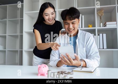 Heureux jeune couple vérifiant les documents financiers et calculant le budget à la maison. payer des impôts, économiser de l'argent concept Banque D'Images