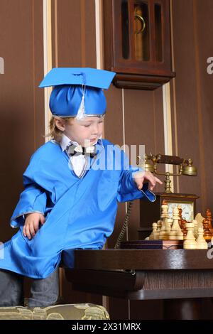Un garçon assis sur une table près du téléphone et jouant aux échecs Banque D'Images